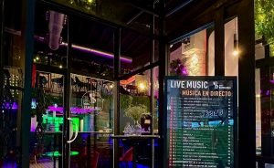 Fachada de Entre Bambalinas iluminada de noche con el cartel de música en directo, en el centro de Alicante